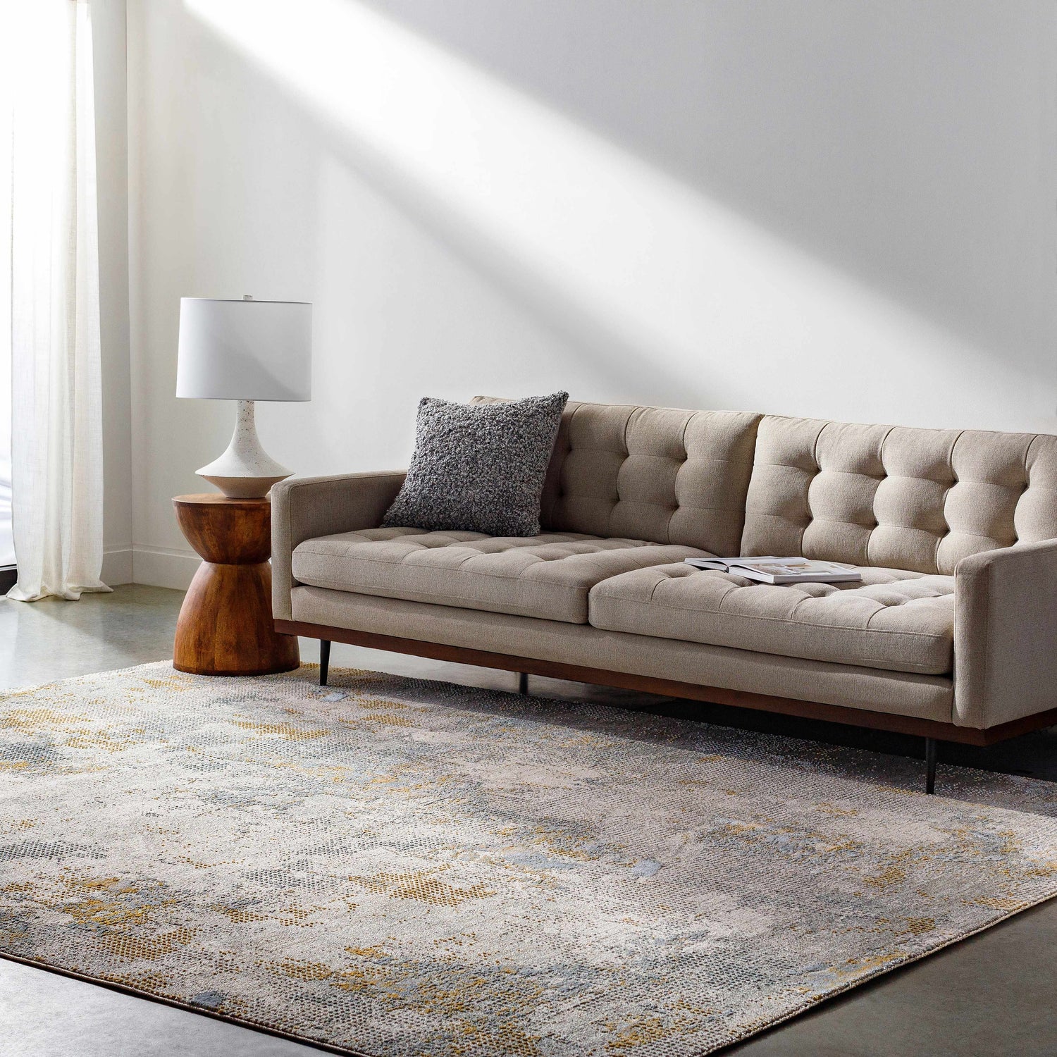 Living room scene with a beige sofa and the Haydn Rock Pattern Rug in gray, brown, and gold tones. Roomscene-Rectangle