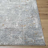 Close-up of the textured Ifama Rug with Fringes. Features gray, light brown and off-white hues on a wood floor. Front