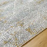 Close up of the Mila Textured Rug with Fringes. Features a gray, white, and gold abstract pattern. Texture