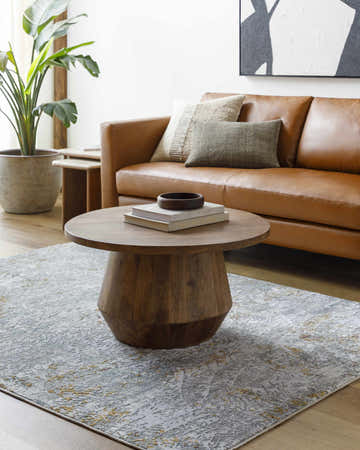 Living room scene with a Moke Textured Rug, brown leather sofa, and round wood coffee table. Roomscene-Rectangle