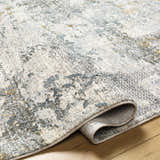 Close-up of the Pizi Textured Rug showing its light gray, ink blue, and mustard contemporary design and soft texture. Fold