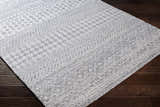 Close-up of the hand-woven Seafield Indoor Outdoor Rug. Gray, off-white, and slate blue bohemian pattern. Corner