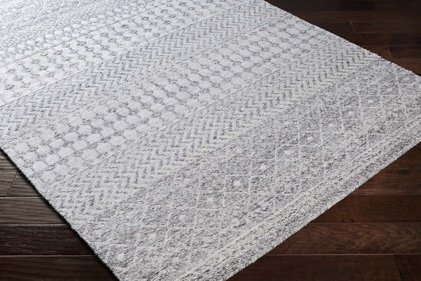 Close-up of the hand-woven Seafield Indoor Outdoor Rug. Gray, off-white, and slate blue bohemian pattern. Corner