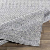 Close-up of the hand woven Seafield Indoor Outdoor Rug showing gray, off white, and slate blue tones and subtle pattern. Fold