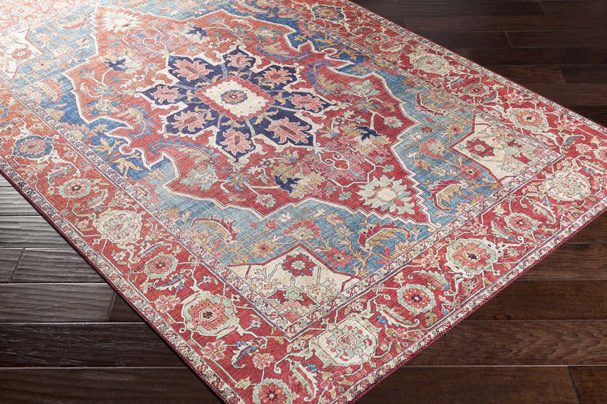 Close-up of the Seattle Area Rug. Traditional style rug in beige, red, and blue on dark wood floors. Corner