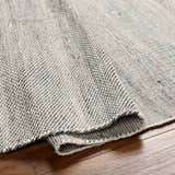 Close-up of the hand-woven Anaya Beige & Teal Area Rug showing texture and pattern details on a wood floor. Fold