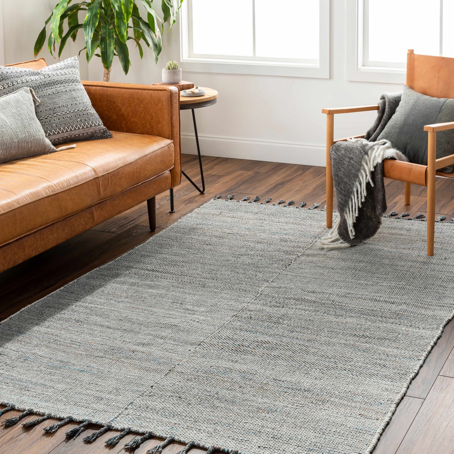 Living room scene with a beige leather sofa and Anaya Beige & Teal Area Rug with tassels on dark wood floors. Roomscene-Rectangle