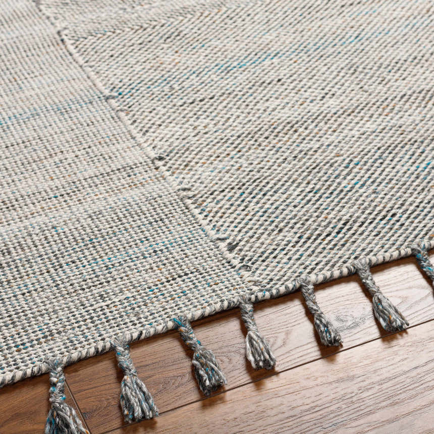 Close-up of Anaya Beige & Teal Area Rug showing woven texture and gray tassels with teal accents on a wood floor. Texture