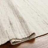 Close-up of the hand-woven Anaya Cream Area Rug. Beige, bone, and gray tones with a subtle stripe texture. Farmhouse style. Fold