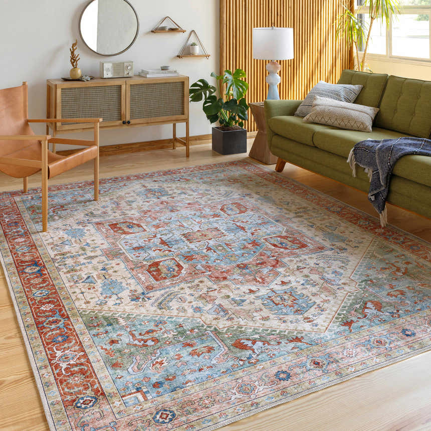 Living room scene with a green sofa and the Bohemian style Selbyville Area Rug in brick red, blue, and beige. Roomscene-Rectangle