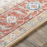 Close-up of the Selbyville Area Rug showing brick red, light beige, and blue oriental pattern and textured fringe. Texture