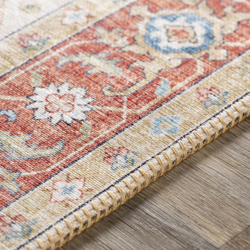 Close-up of the Selbyville Area Rug showing brick red, light beige, and blue oriental pattern and textured fringe. Texture
