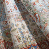 Close-up of the Selbyville Area Rug showing its brick red, emerald, and light blue bohemian pattern. Fold