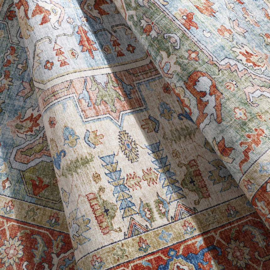 Close-up of the Selbyville Area Rug showing its brick red, emerald, and light blue bohemian pattern. Fold