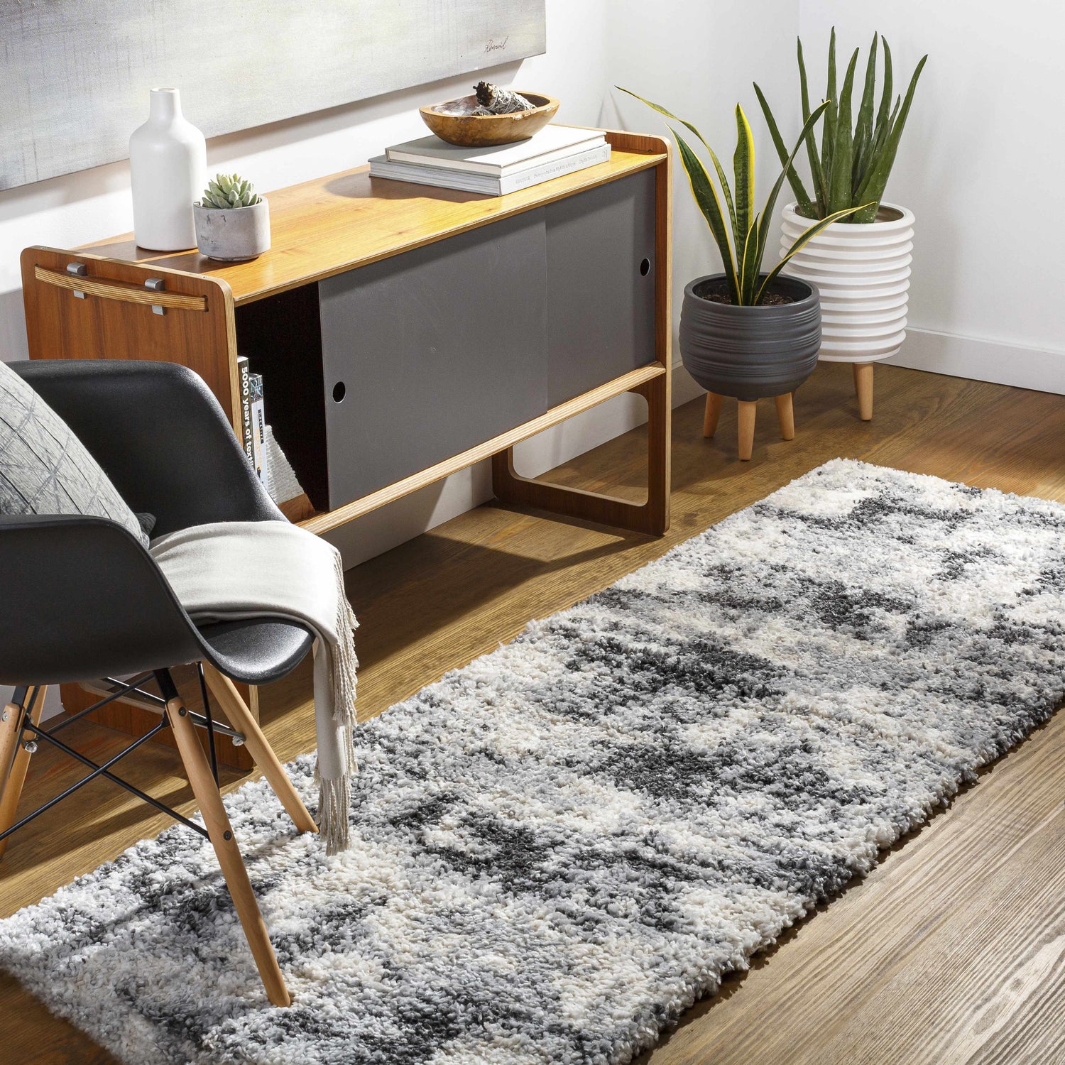 Entryway with wood floors and Selcuklu Area Rug in black, cream, beige, and gray. Contemporary shag rug styled by a cabinet and chair. Roomscene-Runner