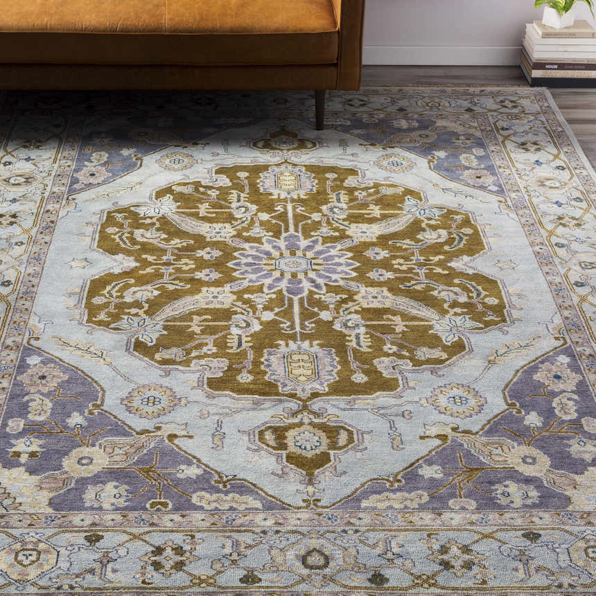 Overhead view of the Senath Area Rug in ivory, mauve, and olive under a brown couch. Hand-knotted wool rug. Styleshot