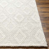Close-up of the hand woven Kasib Cream Area Rug showing its diamond pattern and textured wool blend on wood floor. Front