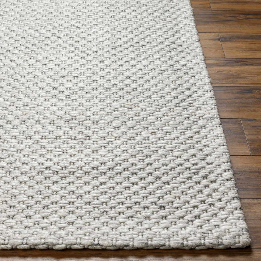 Close-up of the Kassa Gray hand woven area rug showing the texture and pattern on a wood floor. Front