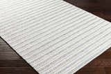 Close-up of the hand-woven Laleh Gray Area Rug showing its beige and rose cream striped pattern and textured weave. Corner