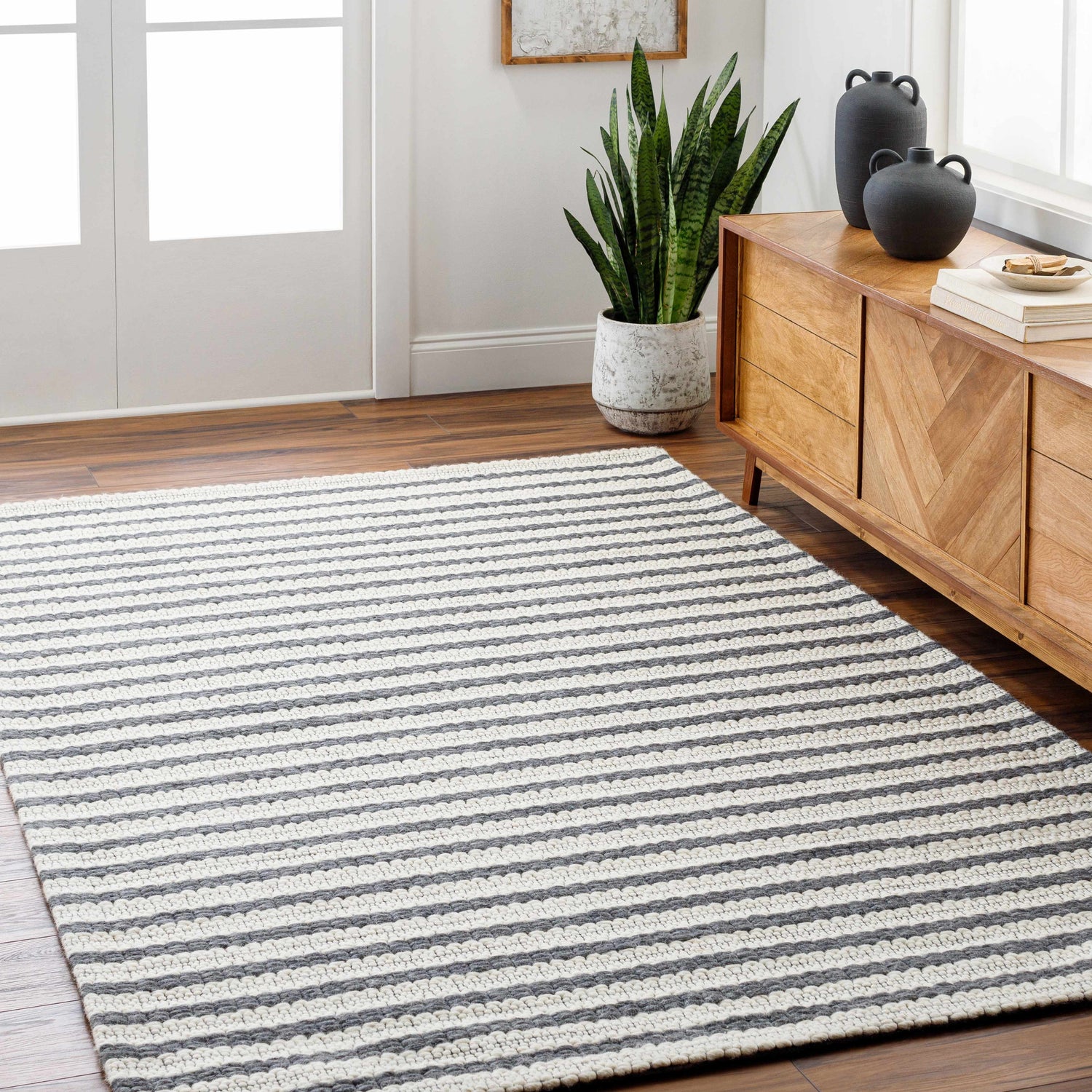 Living room scene with a Laleh Cream & Gray Area Rug, wood floors, and a mid-century modern cabinet with black vases. Roomscene-Rectangle