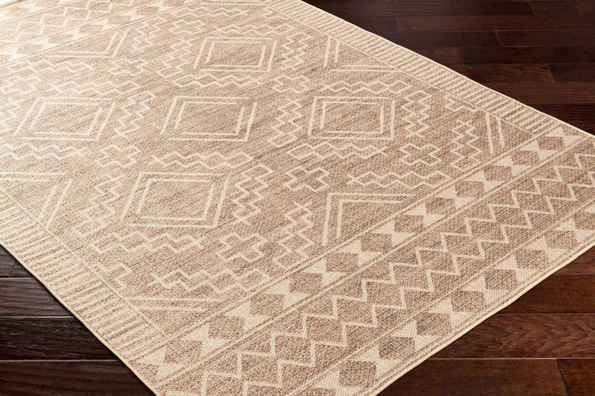 Close-up of the Halle Beige Washable Area Rug, featuring a geometric pattern in oatmeal and brown tones on dark wood floors. Corner