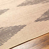 Close-up of the Ijlal Washable Area Rug showing a camel background with a dark brown geometric striped pattern. Texture