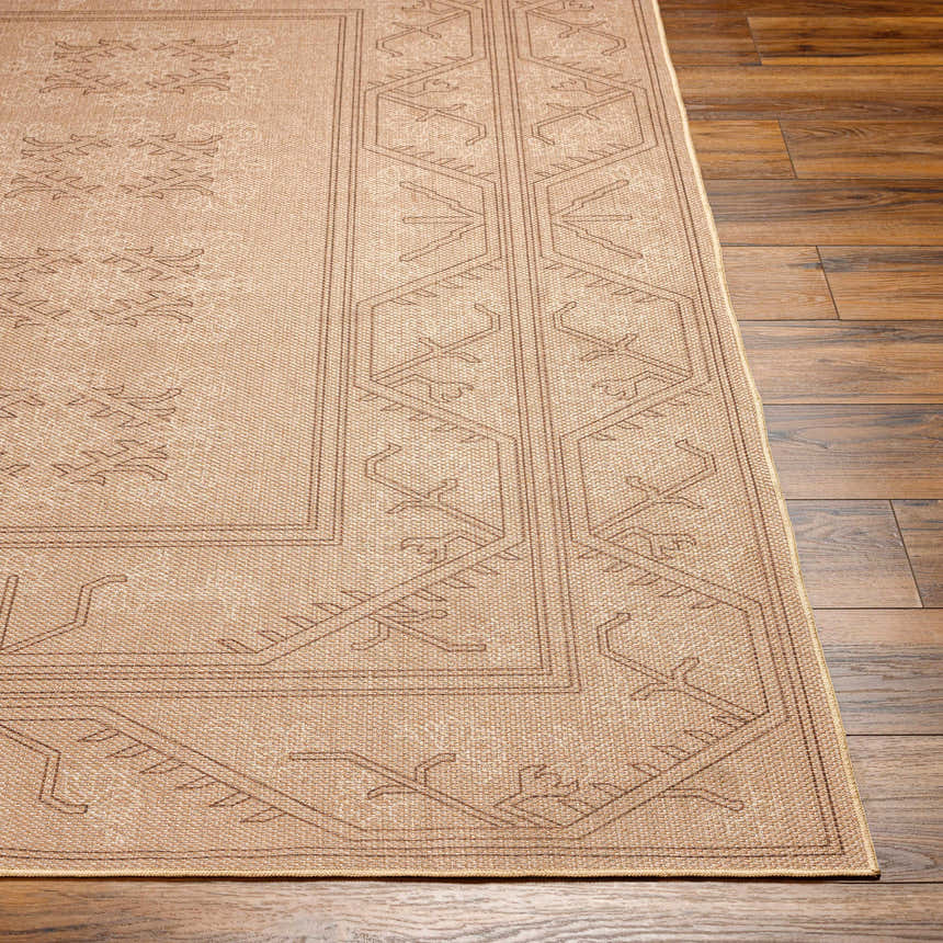 Close-up of the tan Naja Washable Area Rug showing the traditional border pattern and woven texture on dark wood floors. Front
