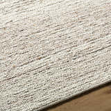 Close up of the hand tufted Urmat Wool Area Rug showing light silver, pearl, and warm gray tones. Texture