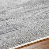 Close-up of the hand woven Chepe Area Rug. Charcoal, light gray, and dark gray recycled PET yarn create a textured pattern. Texture
