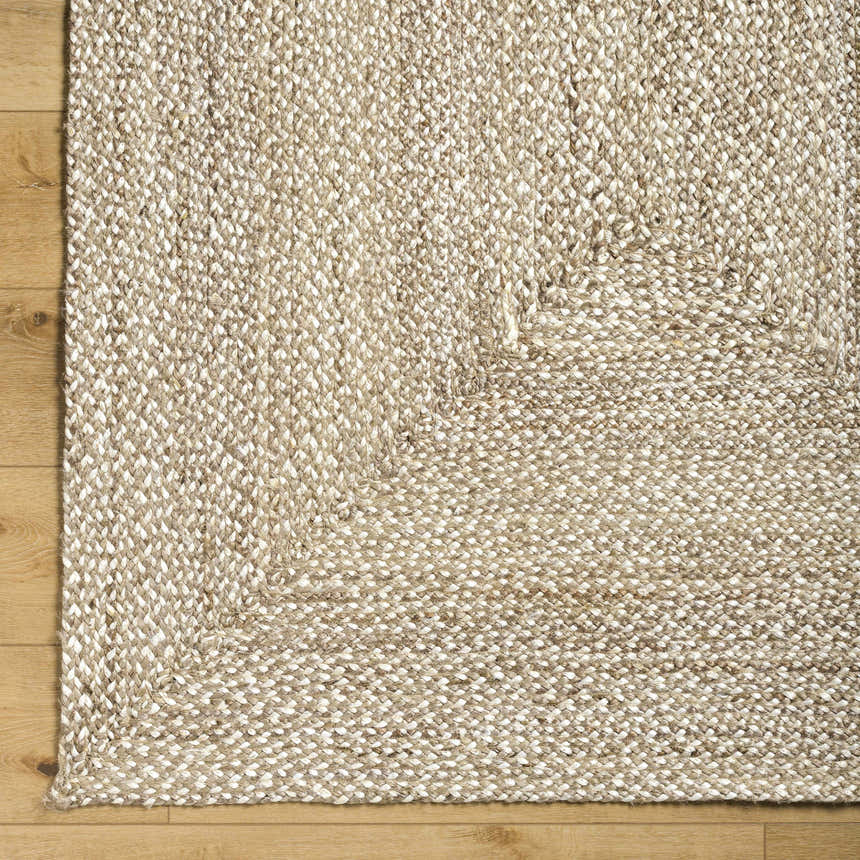 Close up of the hand-loomed Elkie Area Rug showing lambswool and light brown jute texture on wood floor. Corner