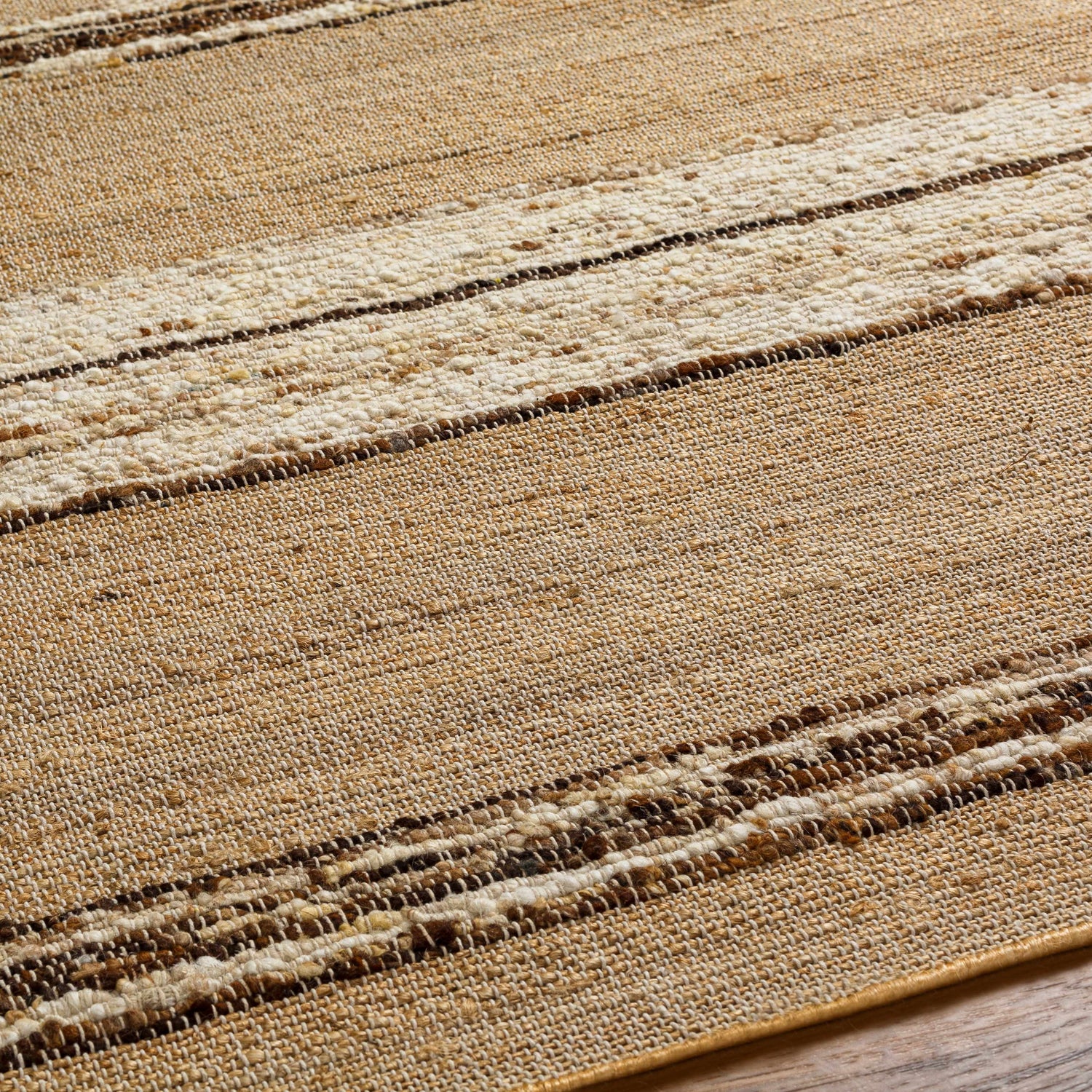 Close-up of the Arnie Area Rug showing a hand-woven, striped design in beige, brown, and ivory tones. Jute and wool texture. Texture
