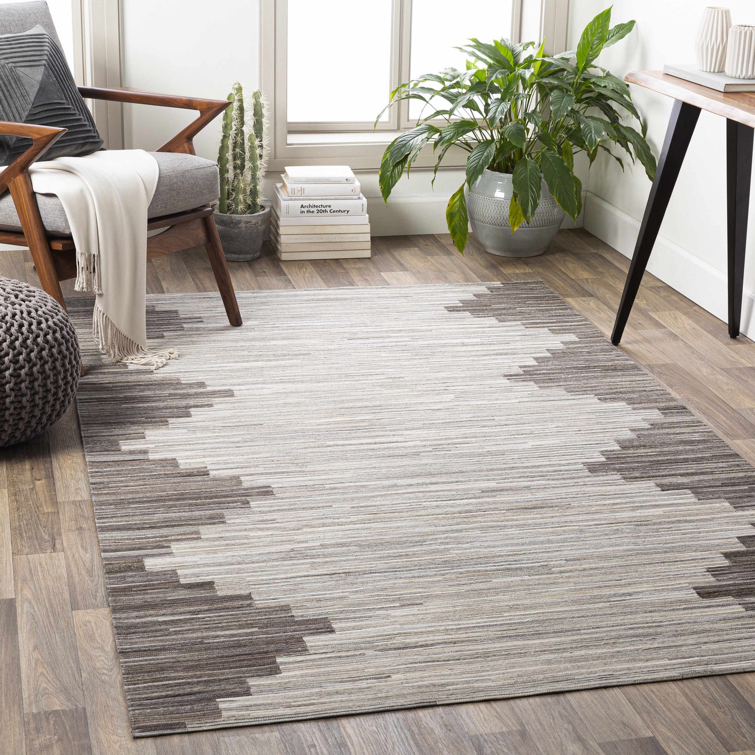 Living room scene with a Shearwater Premium Rug in beige, charcoal, and gray, styled with a chair, plants, and wood floors. Roomscene-Rectangle