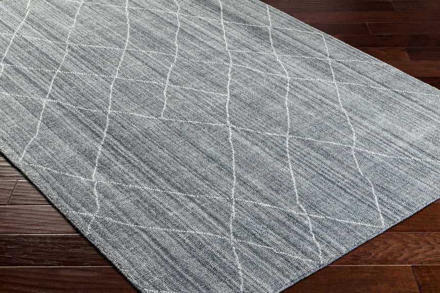 Close-up of Nari Gray Area Rug showing gray tones and white geometric diamond pattern on dark wood floor. Corner