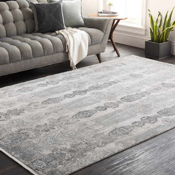Living room scene with gray sofa and Shipdham Luxury Fringed Faux Silk Area Rug in black, charcoal, and gray tones. Roomscene-Rectangle