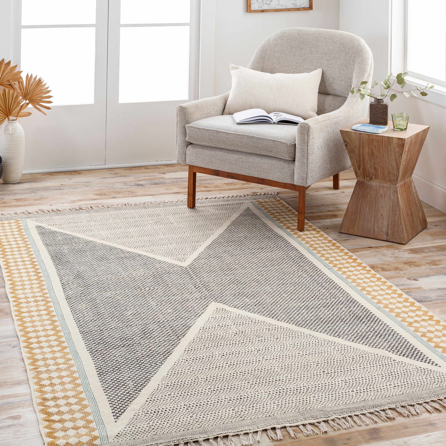 Living room scene with a Sherbrooke Area Rug in black, beige, mustard, and teal, styled under a chair and side table. Roomscene-Rectangle
