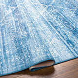 Close-up of the Blake Arctic Sky Washable Area Rug showing its traditional blue and white pattern and machine-woven texture. Fold