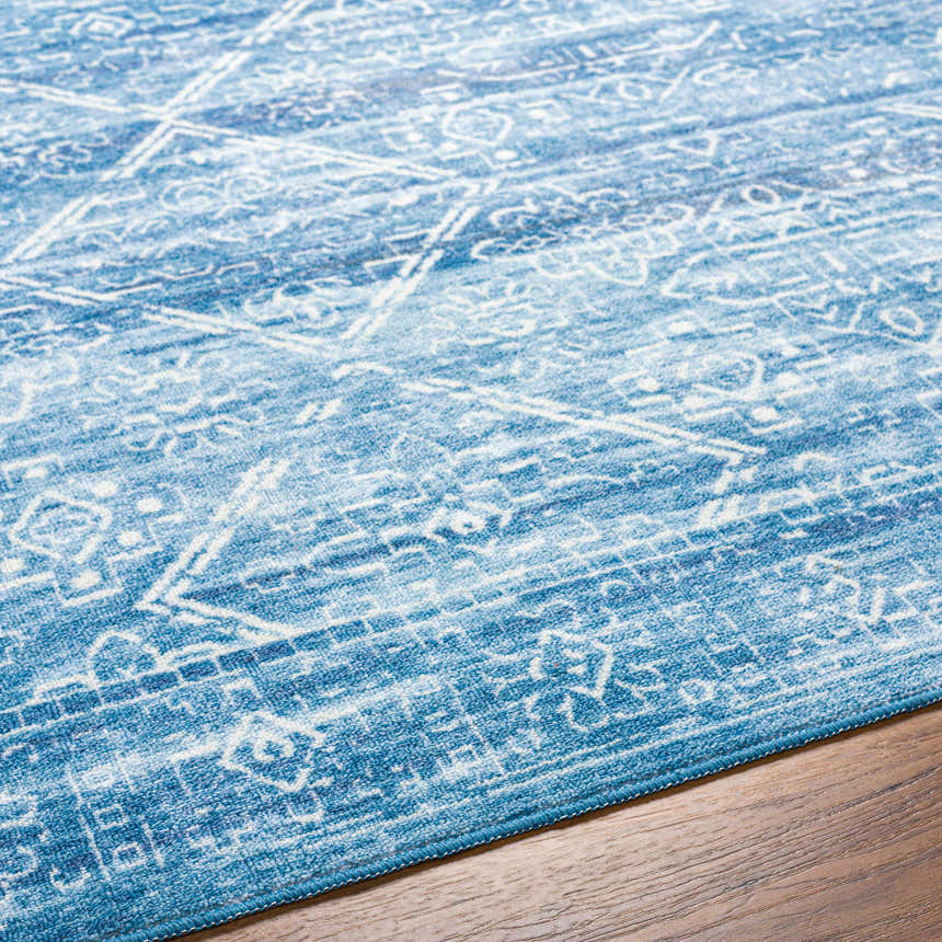 Close-up of the Blake Arctic Sky Washable Area Rug. Features a traditional, farmhouse design in arctic sky and white hues. Texture