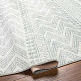 Close-up of the Danon Washable Area Rug showing its arctic stone color and geometric, zig-zag pattern. Fold