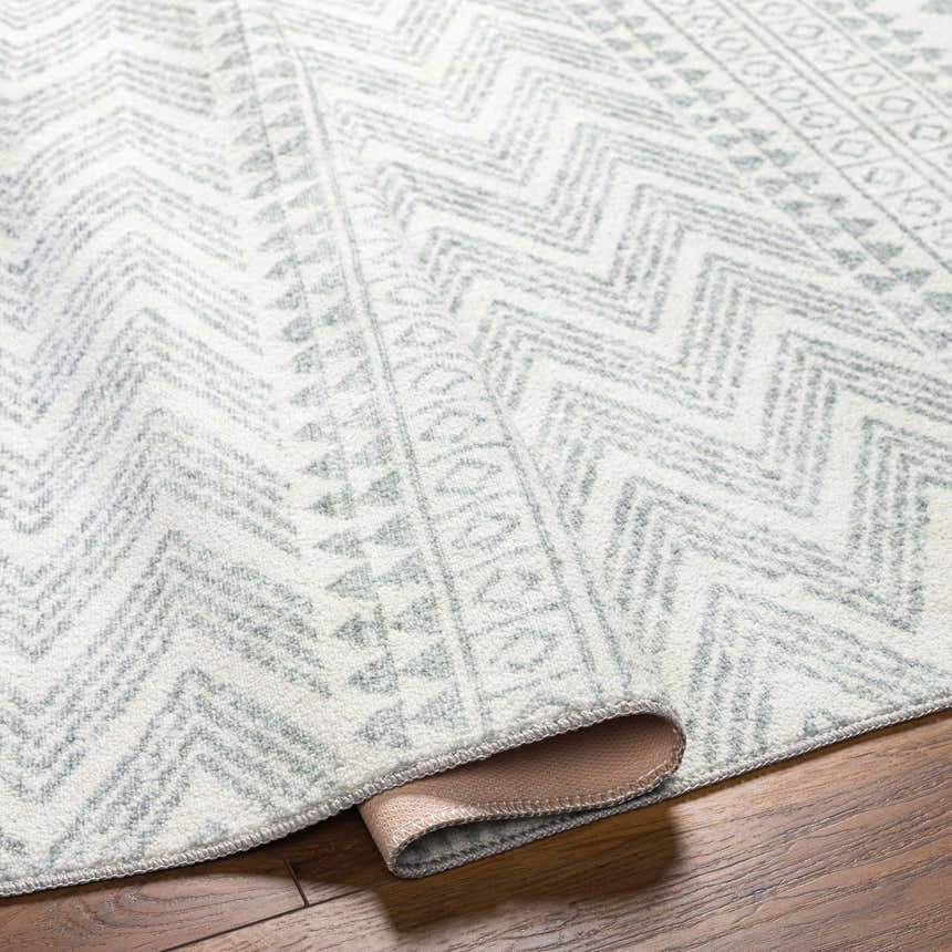 Close-up of the Danon Washable Area Rug showing its arctic stone color and geometric, zig-zag pattern. Fold