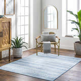 Bright living room with the blue Gizeh Arctic Stone Washable Area Rug, wood cabinet, gold chair, and plants. Roomscene-Rectangle