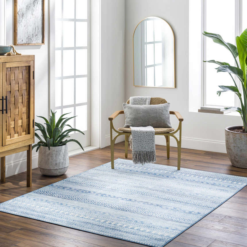Bright living room with the blue Gizeh Arctic Stone Washable Area Rug, wood cabinet, gold chair, and plants. Roomscene-Rectangle