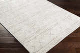 Close-up of the Shortland Premium Area Rug. Hand-loomed cotton and viscose rug in gray, ivory, and taupe with a geometric pattern. Corner