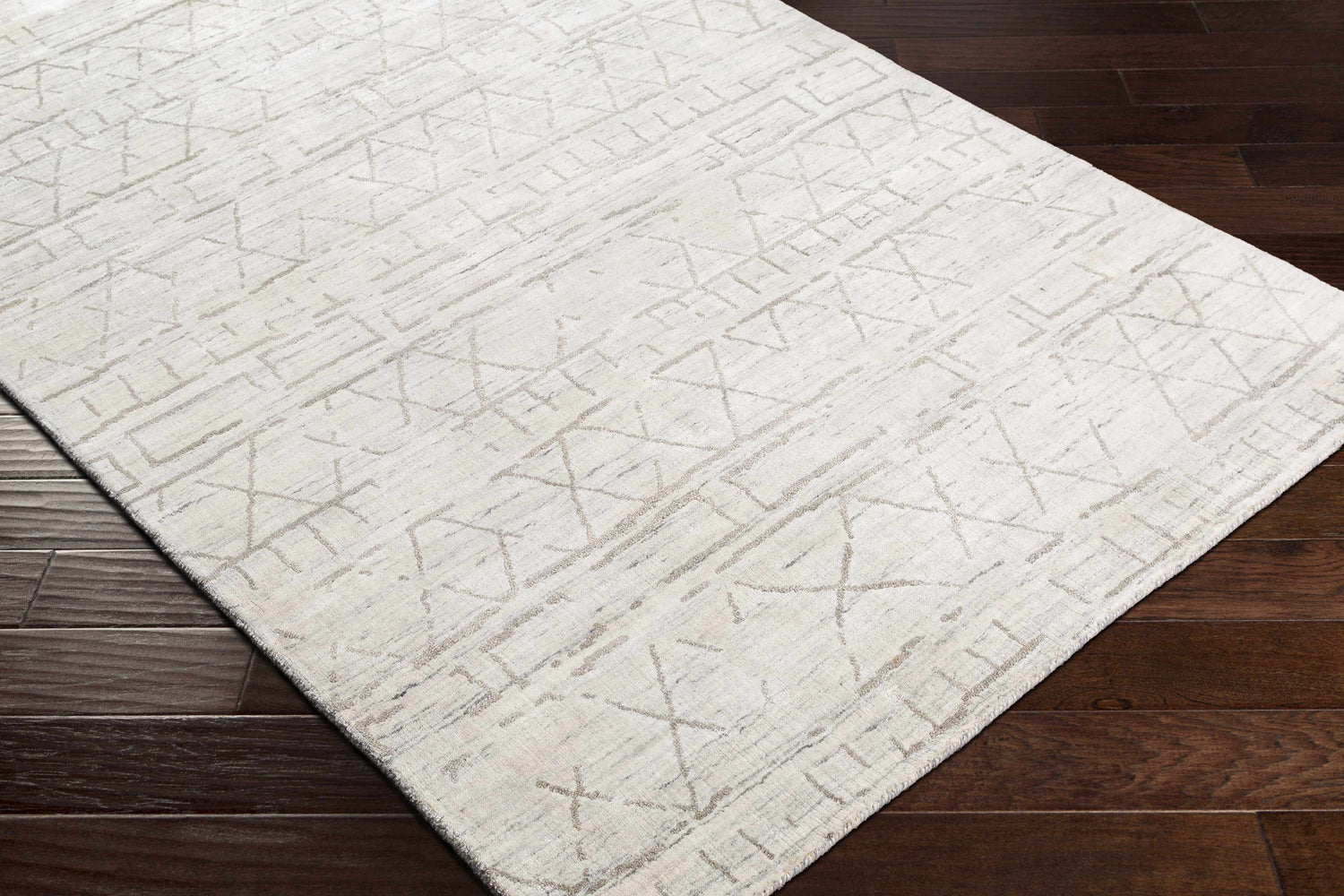 Close-up of the Shortland Premium Area Rug. Hand-loomed cotton and viscose rug in gray, ivory, and taupe with a geometric pattern. Corner