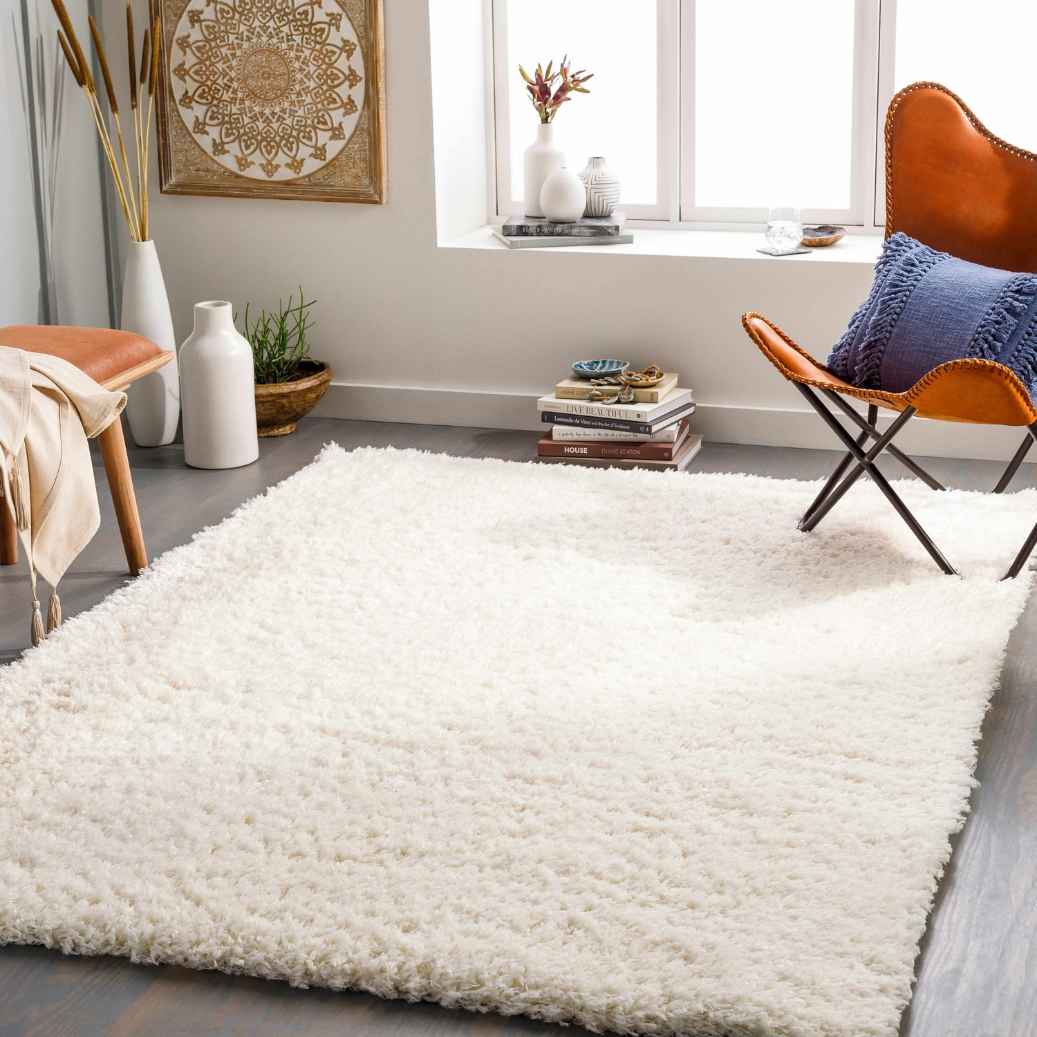 Living room scene with a cream Siari Solid Plush Rug, tan leather chair, and neutral decor. Roomscene-Rectangle
