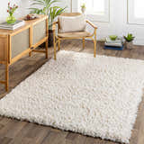 Living room scene with a Siari Solid Cream Plush Rug, wooden cabinet, and chair. Roomscene-Rectangle