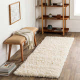 Living room scene with a cream Siari Solid Plush Rug, wooden bench, and bookshelf. Roomscene-Runner