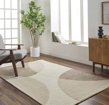 Living room scene with a Cassiopeia Dark Brown & Beige area rug, gray chair, wood cabinet, and large window. Roomscene-Rectangle