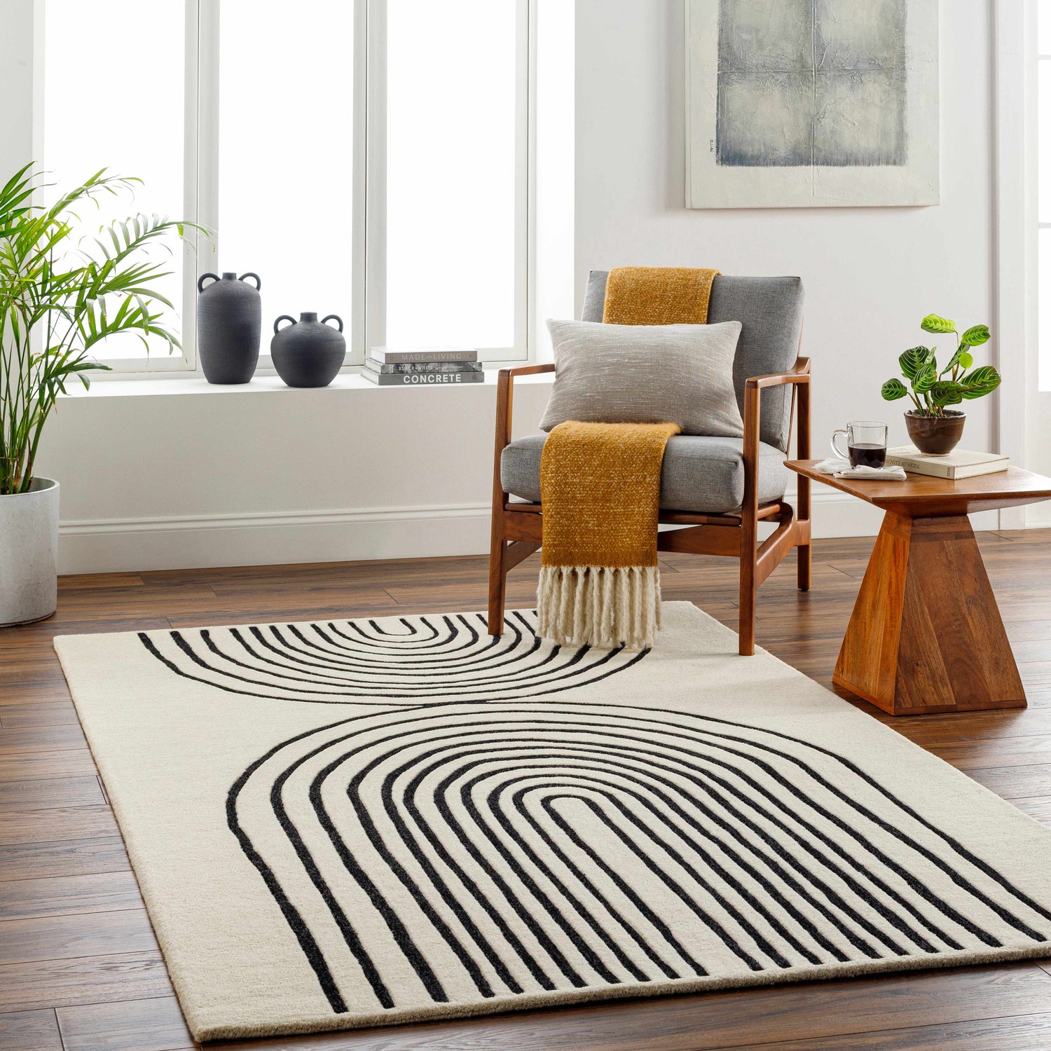 Living room scene with a Fuat Cream Area Rug. The rug has a black geometric pattern and sits under a wood side table and gray armchair. Roomscene-Rectangle