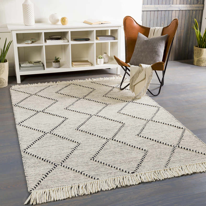 Living room scene with a cream and black geometric Siguinon Area Rug, white shelving unit, and leather butterfly chair. Roomscene-Rectangle