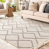 Living room scene with a cream sofa and the Siguinon Area Rug, a hand-woven wool rug with a geometric black and cream pattern. Roomscene-Rectangle
